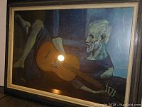 Front view of framed painting showing skeleton playing guitar with light glare on glass.