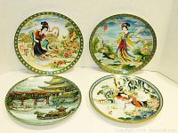 Four Asian-themed collectible plates arranged in two rows, showing distinct designs including women in traditional dress and architectural scenes, with green and gold borders.