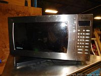 Front view of Panasonic stainless steel microwave oven with visible keypad and display.