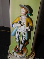 Close-up of the porcelain figurine depicting a boy holding a flower with detailed clothing and base.