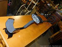 Metal detector laying flat on wooden table showing padded arm support and control panel.