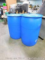 Front view of two blue plastic barrels in a warehouse setting, showing color and shape for rainwater collection.