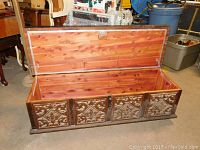 Front angled view of Lane cedar chest with lid open showing cedar-lined interior and ornate carved front panels.