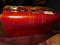 Photo of the large vintage reddish-brown leather suitcase showing handle and stitching detail.
