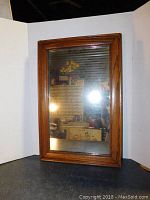 Full front view of the antique mirror showing rectangular shape, wood frame, and reflective glass surface.