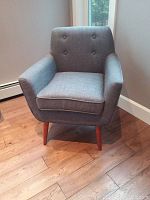 Front view of grey armchair showing button-tufted back, seat cushion, arms and legs