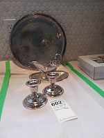 Photo showing the silverplated serving platter standing upright with the gravy bowl in front and a pair of Birks candlestick holders alongside. All have a reflective polished surface and visible beaded edge detailing on platter and candlesticks.