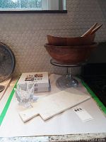 Photo showing stacked large and smaller wooden salad bowls with wooden utensils inside, marble cheese board lying flat, glass dip baker and original box alongside
