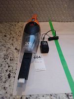 Front view of Bissell handheld vacuum with 20V Lithium Ion marking, transparent dirt container, and charger on countertop.