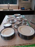 Overview of full set on countertop showing plates, cups, saucers, bowls and serving dishes