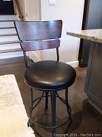 Front view of one stool showing wooden backrest and padded seat