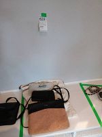 Three purses and two wallets arranged on a flat surface showing fabric Roots tote, Pixie and Mood cork and leather purse, and wallets