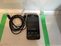 Samsung Galaxy Core phone front view with USB charging cable on white background.