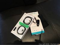 Photo of Fitbit Flex 2 packaging with the tracker, wristband, and an older model Fitbit Tracker placed beside the box on a black surface.