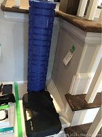 Overall shot showing black Pro Tens carrying case with Pro Tens device and blue Pure Athletics muscle roller next to stairs.