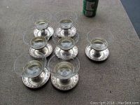 Six assembled sterling silver dessert dishes with clear etched glass bowls on a table.