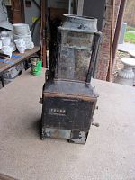 Front-side view of the antique coin operated bus fare collector, showing the mechanical counter and crank handle, with worn and rusted metal surfaces.