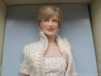 Close-up of Princess Diana doll head and upper torso wearing an off-white beaded gown and jacket, showcasing detailed facial features and earrings.