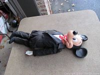 Full body image of the Mickey Mouse ventriloquist doll lying down, showing black suit and shoes.