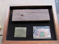 Wooden stadium seat back piece with grain texture mounted on display with photo of Palmer Stadium.