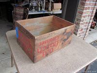 Full view of the wooden crate on a table, showing the interior and exterior markings.