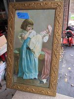 Full view of framed print showing child in blue dress holding a doll in white and pink bonnet, ornate frame visible