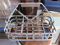Top-down view of the metal milk bottle carrier showing the metal slats and wooden handle base.