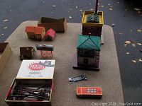 Overview photo of the lot showing multiple model buildings, water tower, parts box, and small Lionel box