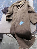 Full view of the US Army wool overcoat laid on table, showing its length and condition.