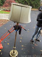 Full view of the floor lamp showing the fabric lampshade, brass stand, and outdoor setting.