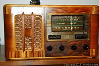 Front view of radio showing wood cabinet, cloth speaker grille and tuning dial