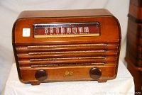 Front three-quarter view of walnut radio showing horizontal grille slats and tuning dial