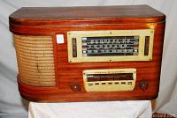 Front view showing wooden cabinet, mesh speaker grille, tuning dial with push buttons, knobs, and General Electric branding.