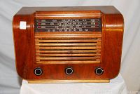 Front view of wooden cabinet radio showing speaker grill, tuning dial and control knobs