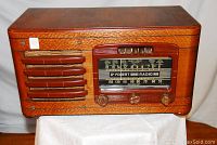 Front view of radio showing wooden cabinet, speaker grille and tuning dial