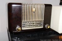Front view of Philips Model PH102 radio showing dark brown bakelite casing, beige front grills, two amber-coated tuning knobs, and frequency dial.