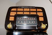 Front view of General Electric Model C220 radio showing tuning dial and control knobs on the black Bakelite case with fabric speaker grille.