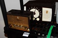 Two vintage radios positioned side-by-side, Westinghouse with rectangular brown plastic case and clock face, Zenith with dark Bakelite case and large circular dial.