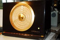 Front view of black bakelite cabinet with gold-tone speaker grille and AM dial