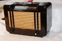 Front angled view showing woven speaker grille and control knobs on radio.