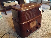 Front side of the Stewart Warner tombstone style radio showing the brown marbled Bakelite cabinet and four control knobs.