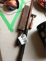 Photo shows German belt sharpening strop in box, wooden hammer, and shot measure dipper together on a flat surface