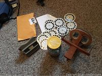 Lot overview showing antique Mercury stereoscope, jar of vintage marbles, Viewmaster viewer, and multiple slide reels.