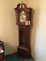 Full view of grandfather-style clock standing against wall, showing overall height and case design.