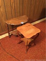 Two solid wood tables placed on red carpet against wood-paneled wall showing their overall size and style