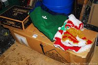 Photo showing stacked Christmas tree skirts in green, red, white, and gold colors, along with their packaging and surrounding items.