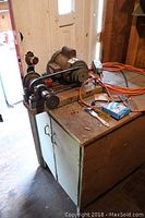 Wide-angle view of the Doerr grinder setup on a metal cabinet including motor, belt drive, grinding wheels, and attached power cables.