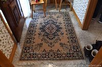 Overall view of the Gloria branded area rug placed on tiled floor showing general design and wear.