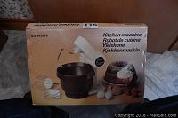 Siemens branded box displaying the Kitchen Machine product, including images of the machine, bowl, and dessert sample.