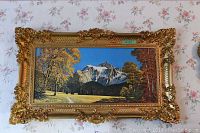 Framed landscape print showing mountain with snow-capped peaks and yellow and orange autumn trees under blue sky.